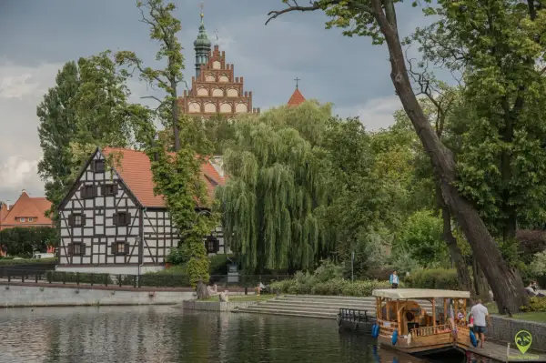 Nietypowe atrakcje Bydgoszcz: malowniczy widok na Brdę z zabytkową architekturą i łodzią.