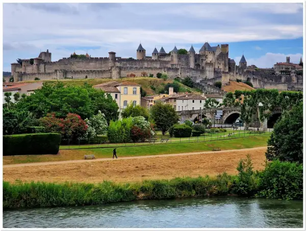 Majestatyczna twierdza Carcassonne góruje nad miastem, otoczona zielenią i rzeką.