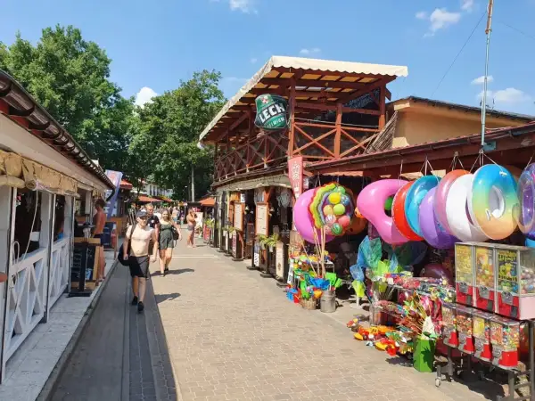 Skorzęcin atrakcje: kolorowe koła do pływania, zabawki i budki z grami na deptaku. Słoneczny dzień zachęca do spacerów.